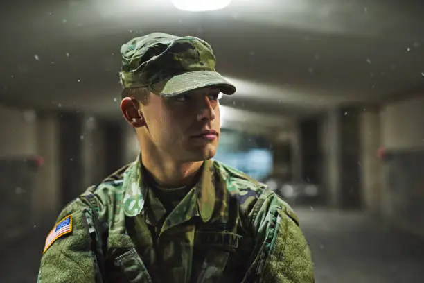 Shot of a young soldier standing outside on a cold night at a military academy
