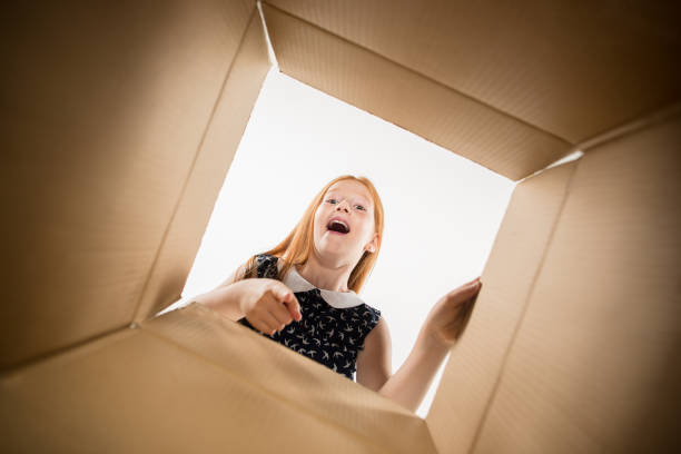 istock The girl unpacking and opening carton box and looking inside 1015451348