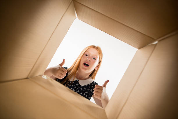 istock The girl unpacking and opening carton box and looking inside 1015451380