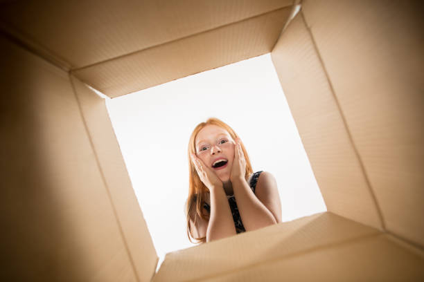 istock The girl unpacking and opening carton box and looking inside 1015451482