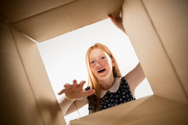 istock The girl unpacking and opening carton box and looking inside 1015451682