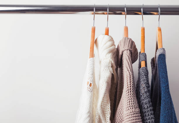 istock Knitted sweaters on hangers on the white wall background 1015455300