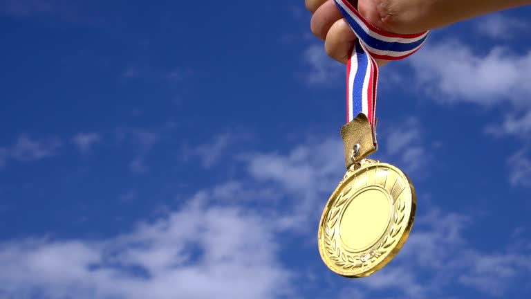 Winners Champion in success award concept : Businessman hands raised holding gold medals with ribbon against blue sky background to show success in sport or business, Slow motion video