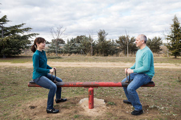woman and man mounted on a seesaw maintaining equality stock photo