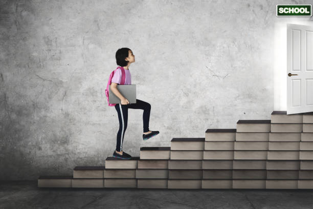 la studentessa carina porta un laptop sulla scala del libro - book child staircase steps foto e immagini stock