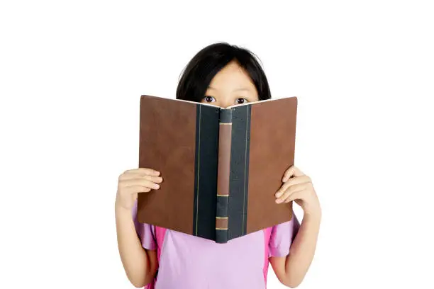 Picture of little girl reading a book while peeping out of a book, isolated on white background