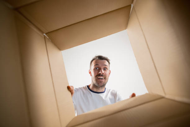 istock Man unpacking and opening carton box and looking inside 1015496360