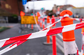 Roadworks concept: orange safety bollards and yellow sign on roadside.