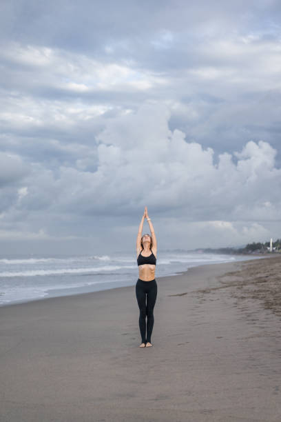 istock beautiful young woman practicing yoga in Mountain pose (Tadasana) on seashore 1015534284