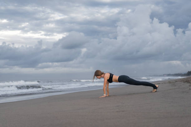 istock side view of young woman practicing yoga in plank pose on seashore 1015534494