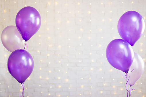 purple air balloons over white brick wall background with lights
