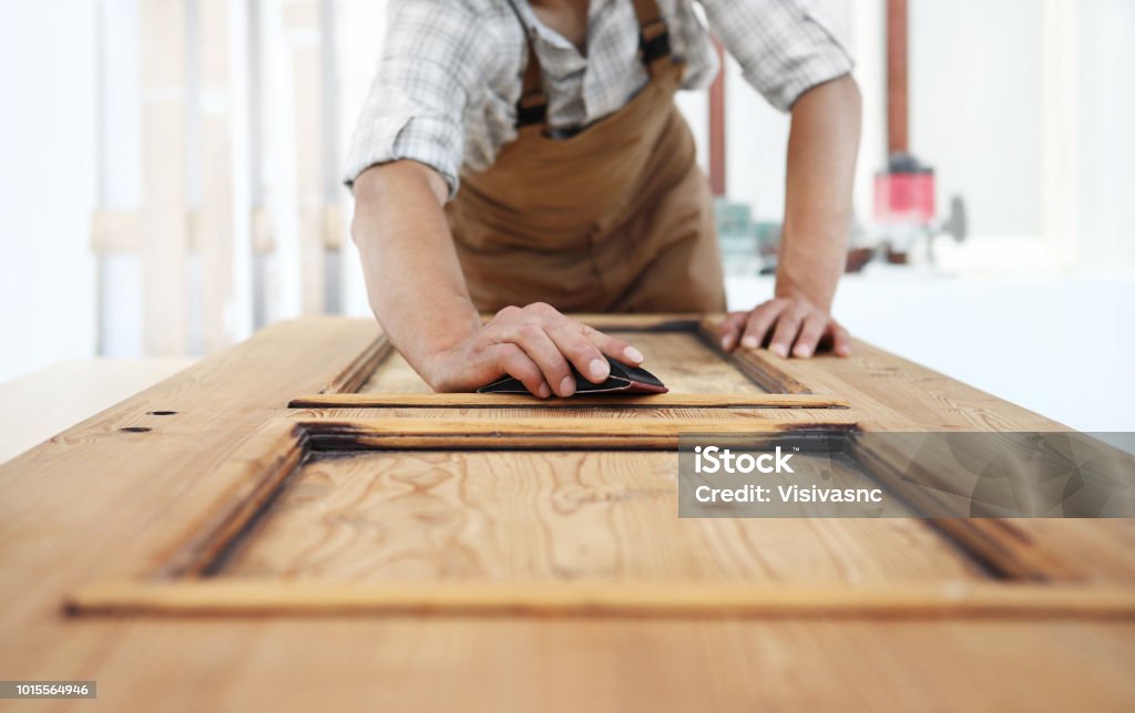 carpenter work the wood with the sandpaper Door Stock Photo