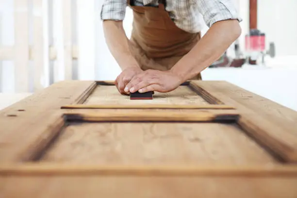 Photo of carpenter work the wood with the sandpaper