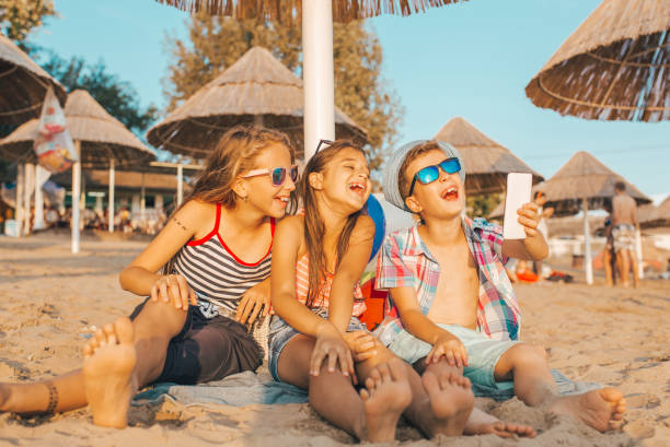 istock Kids playing with mobile phones on sandy beach 1015565634