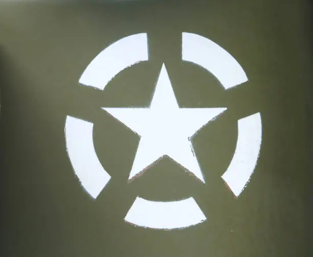 Photo of a white US army star in an invasion circle stenciled on an olive green painted military vehicle