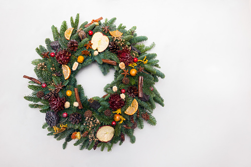 Beautiful hand made Christmas wreath isolated on white background, green spruce branches decorated with pine cones and other decorations