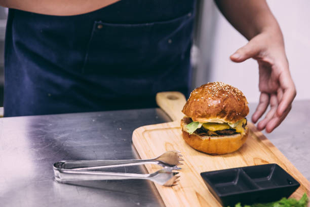 istock Chef making a beef cheeseburger on wooden plate. 1015585540