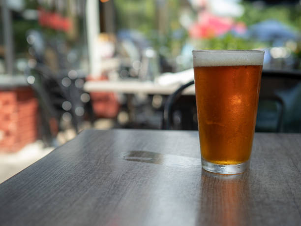 istock Ice cold amber beer sitting in a pint glass on a table outside with wet cup ring 1015585568