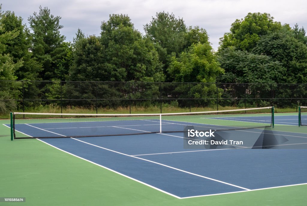 Pequeña, cancha de tenis de asfalto azul barrio rodeado de verde - Foto de stock de Tenis libre de derechos