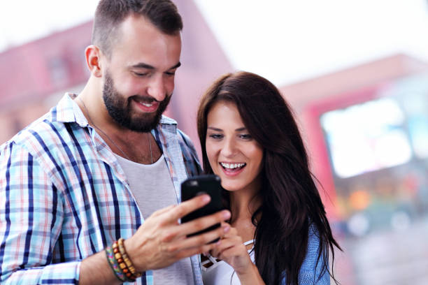 istock Happy couple using smartphone in city in rainy day 1015589786