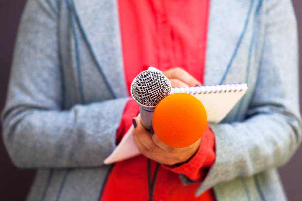 istock Female journalist at news conference, writing notes, holding microphone 1015589840