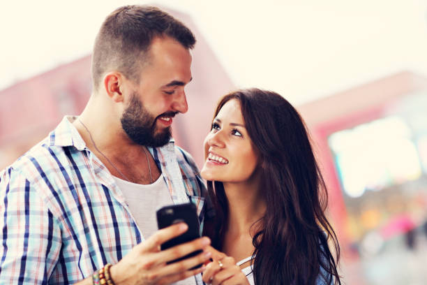 istock Happy couple using smartphone in city in rainy day 1015594136