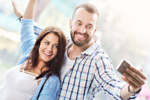 istock Happy couple using smartphone in city in rainy day 1015594334