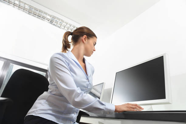 blonde woman standing in the office typing something on the computer