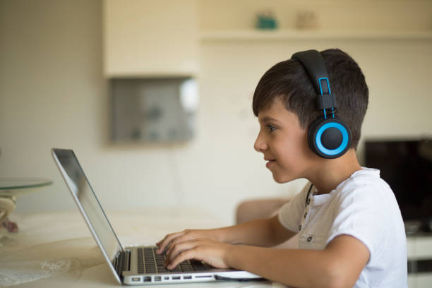 istock Boy plays video games on gaming computer while wearing headphones 1015604126