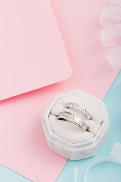 istock Two silver wedding rings with diamonds on pink background 1015612590