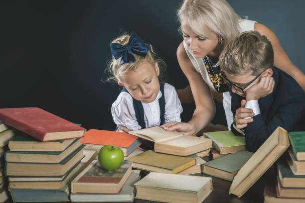 istock Mother or teacher helping for school kids doing homework, reading 1015613246