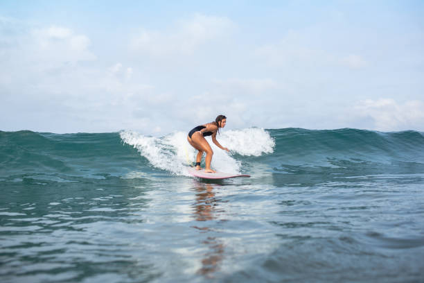 istock attractive young woman riding on wave on surfboard in ocean 1015621304