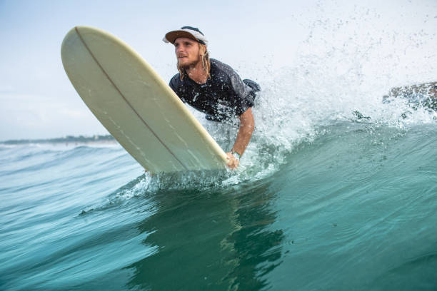 istock young handsome man riding surfboard in ocean during summer vacation 1015621314
