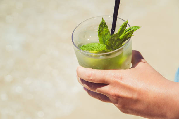 istock Hand holding mojito cocktail on the beach 1015621616