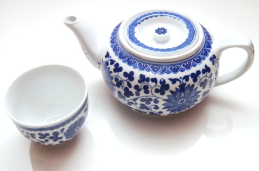 Close-up of a single empty bone China footed tea cup and saucer with a flower pattern, made in England, from directly above standing on a wooden table