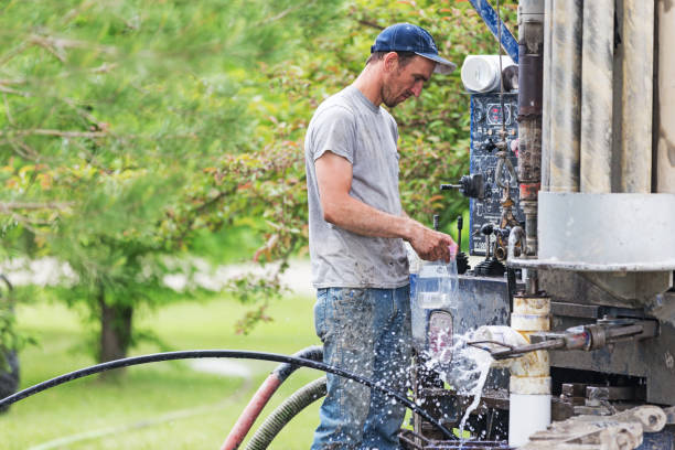 Drilling a New Residential Water Well Erskine, USA - May 30, 2018: A well driller is collecting water samples for testing from a new freshly drilled private residential water well. water well drilling truck stock pictures, royalty-free photos & images