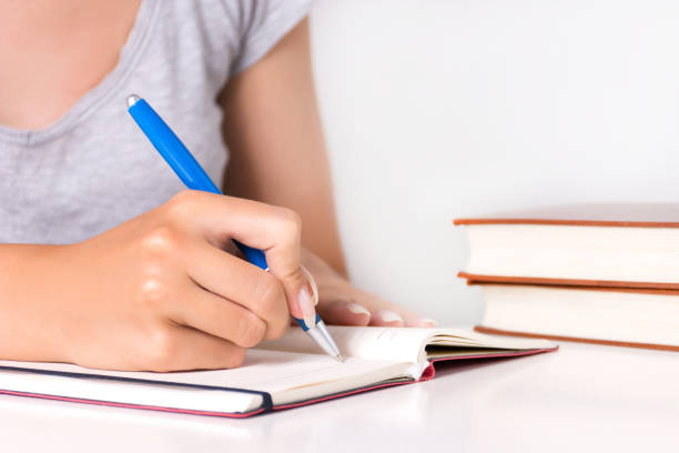 istock Young female student writes in notebook on desk with book 1015708414