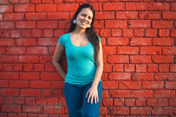 istock Eurasian woman standing against red brick wall. 1015730218