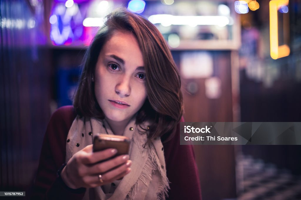 Girl in a bar A girl looking to the camera using your cellphone in a bar. This photo represents social interactions, technology in social world and a comum social life Portrait Stock Photo