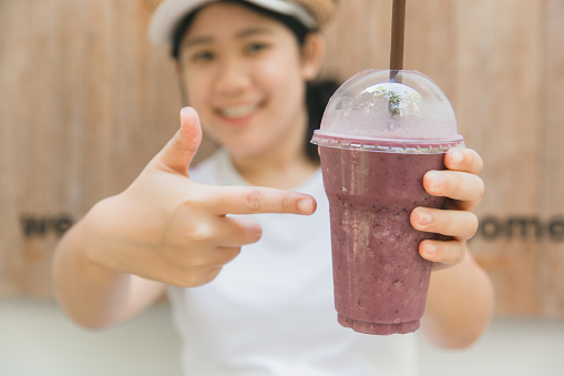 cute teen hand holding healthy drink in summer fruity blueberry smoothie
