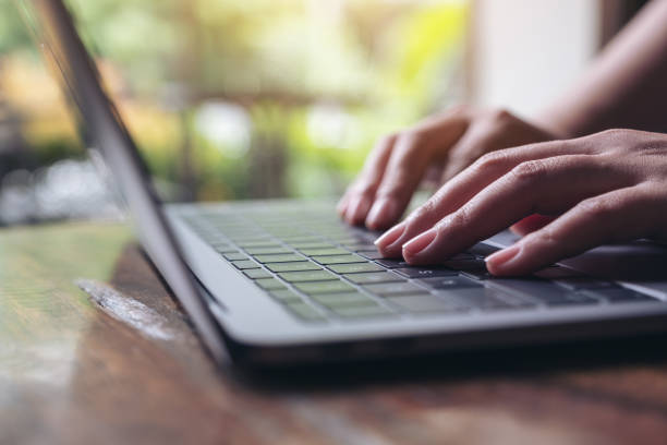 istock Closeup image of hands using and typing on laptop keyboard on wooden table 1015836796