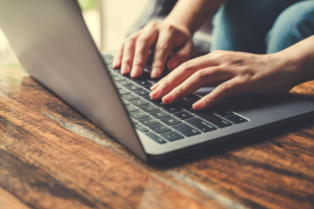 istock Closeup image of hands using and typing on laptop keyboard on wooden table 1015839194