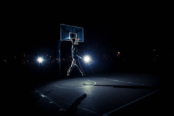 istock Young man playing basketball at night 1015839242