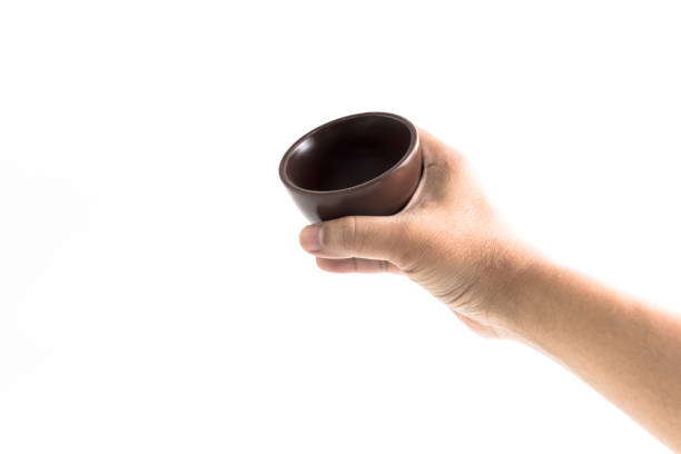 Hand of man is holding the brown ceramic cup isolated