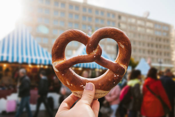 una niña o una joven sostiene un pretzel alemán tradicional - pretzel german culture food salt fotografías e imágenes de stock