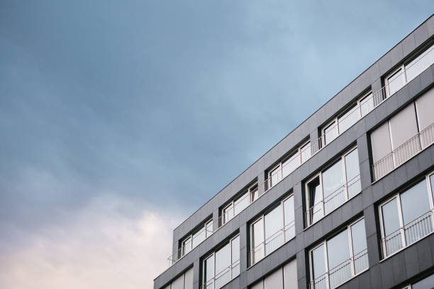 The corner of the building with many windows in a minimalistic style against the backdrop of the setting sun.