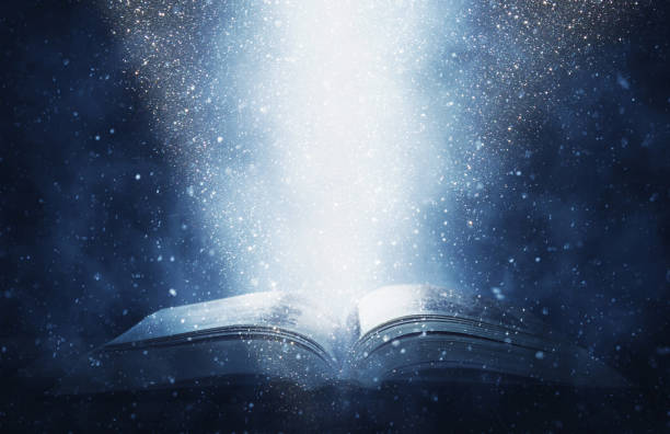 istock image of open antique book on wooden table with glitter background 1015855236