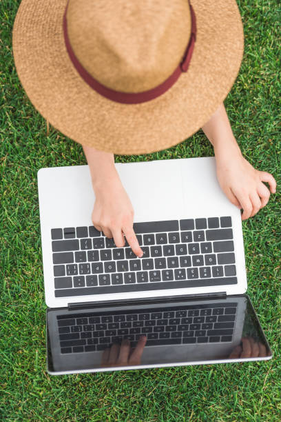 istock overhead view of kid in hat using laptop on green grass 1015856304
