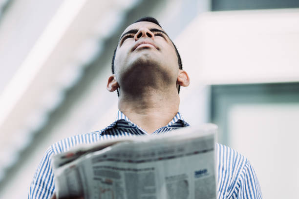 istock Serious Hispanic Man with Newspaper Looking up 1015858452