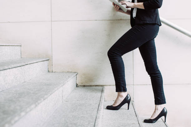 Businesswoman walking upstairs and using touchpad